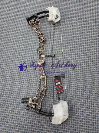Camo compound bow with protective wrapping on a blue textured floor.”